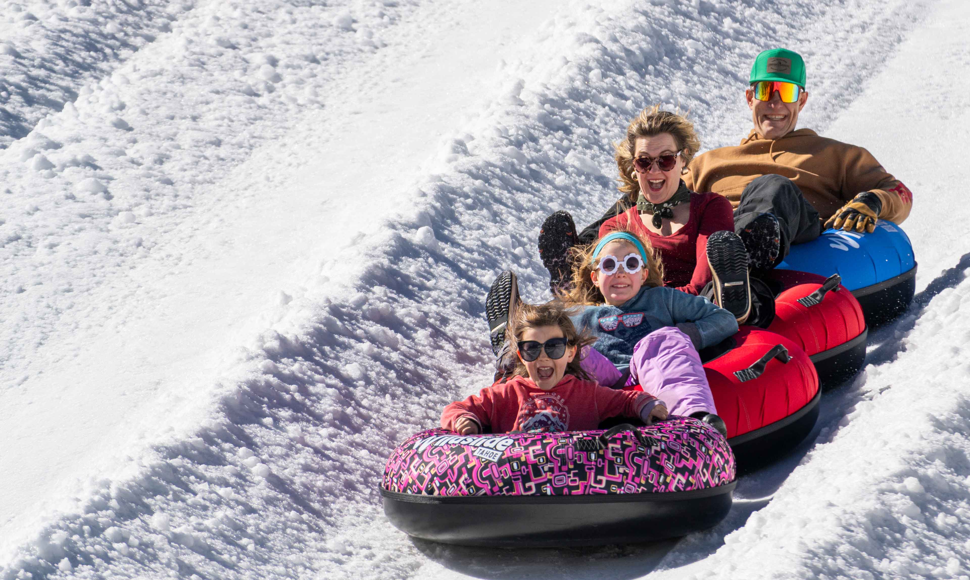 family on tubes sliding down at wildslide tahoe snow tubing