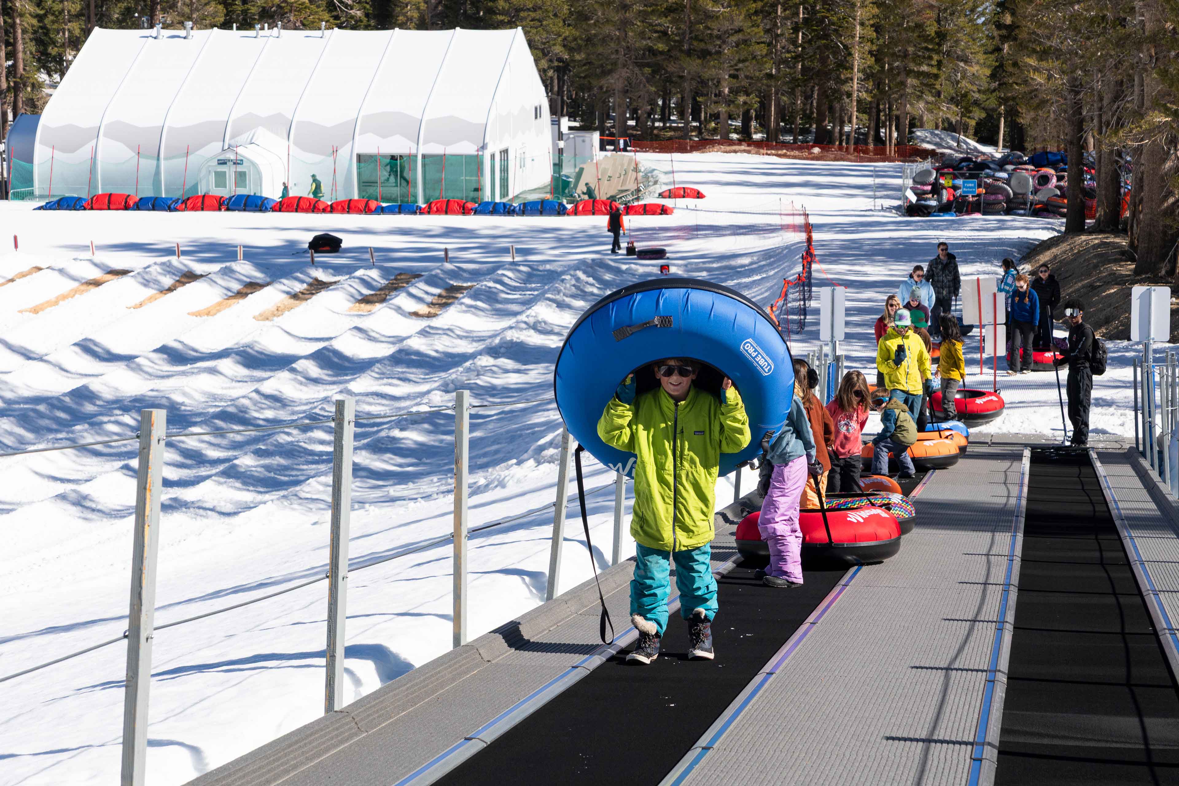 people carrying their tubes to go and slide down the snow lanes